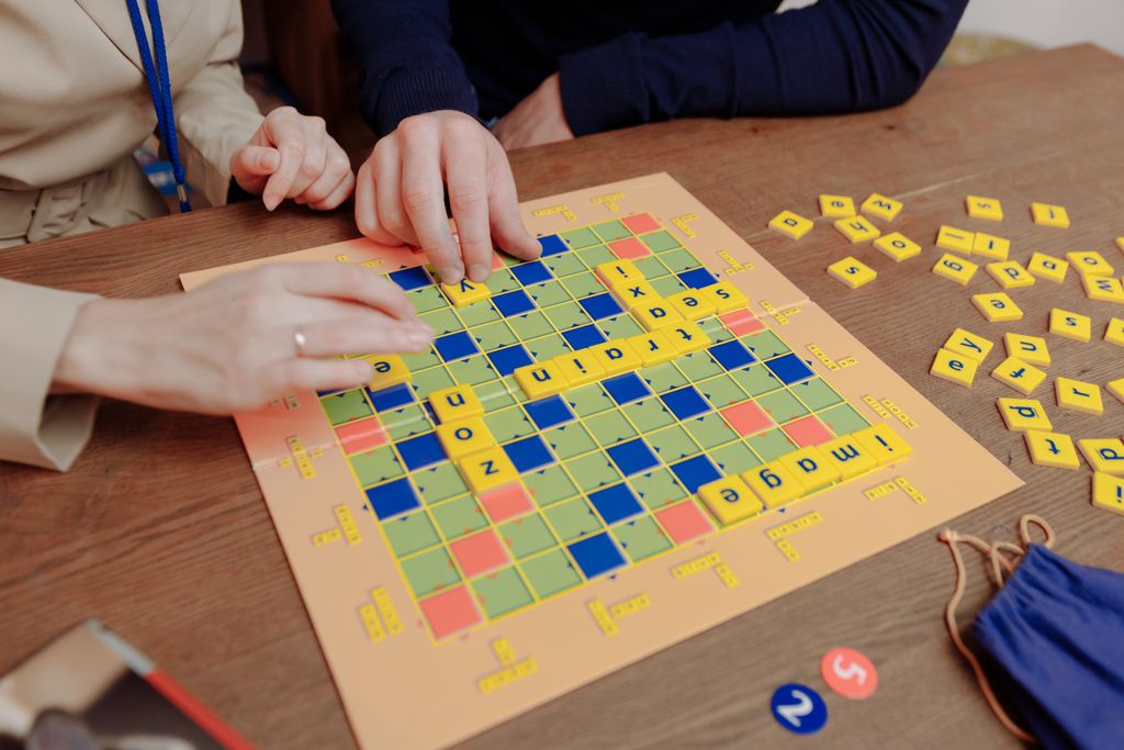A close-up of people playing a word board game indoors, enhancing cognitive skills.