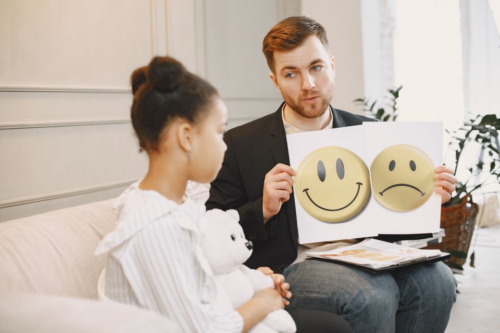 A therapist uses emotion cards to help a child express feelings during a counseling session.