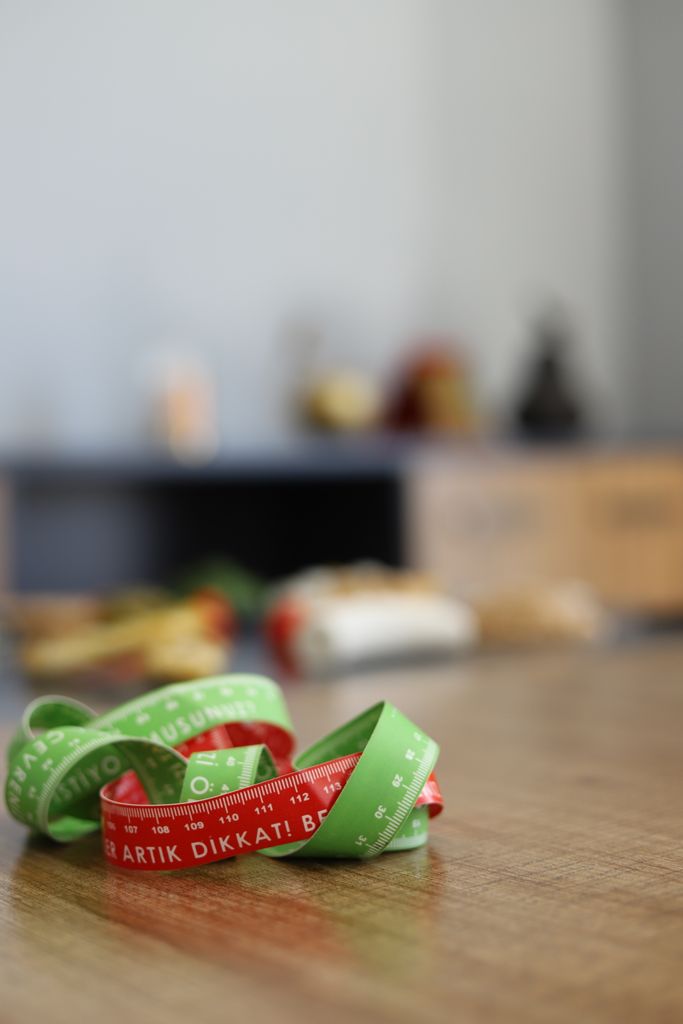 A vibrant measuring tape lies on a wooden table with blurred background items.