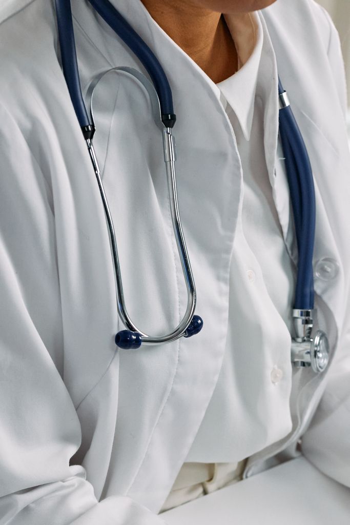 Close-up of a healthcare professional's stethoscope draped around a white coat, symbolizing clinical care.