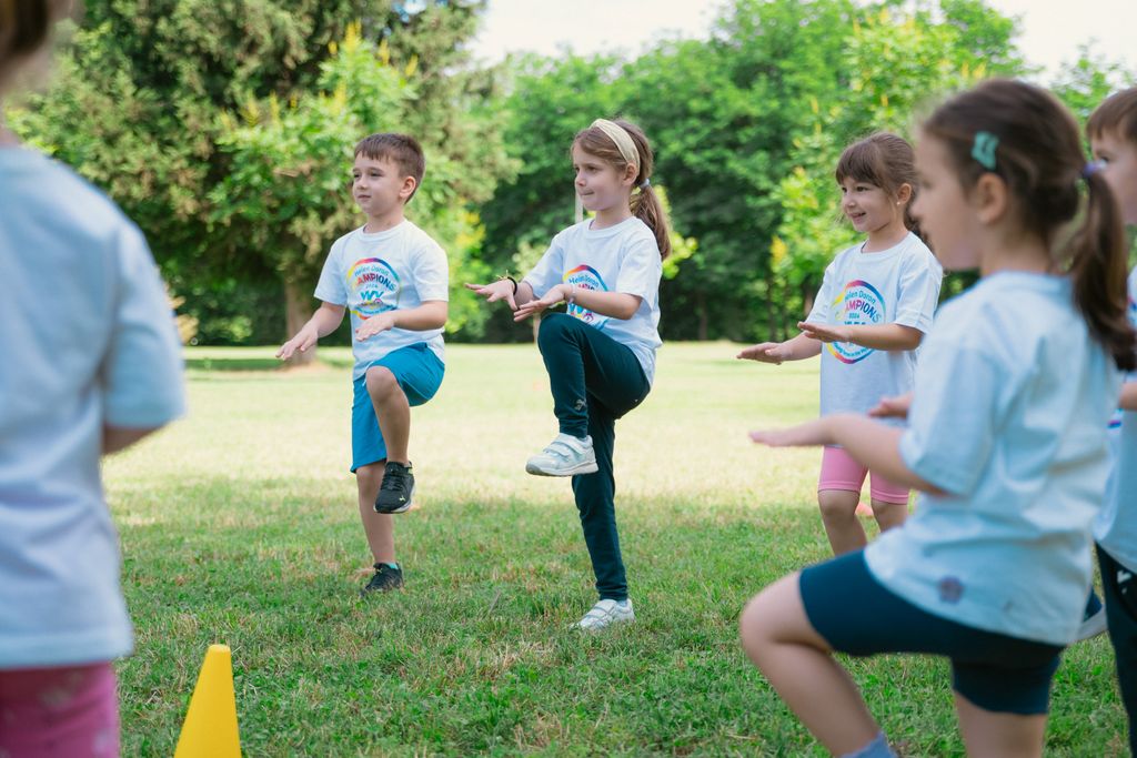 Group of children playing and exercising outdoors in a sunny park setting.