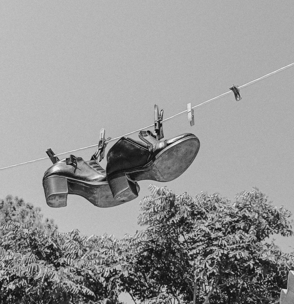 Monochrome image of shoes hanging on a line against a clear sky in Baku, Azerbaijan.
